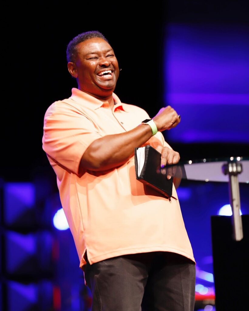 Pastor Bill Ray Rhema Bible Church orange shirt with bible on his hands