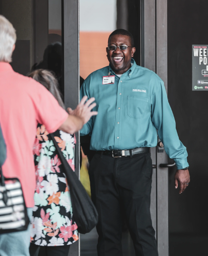 Volunteer smiling at the door of Rhema Bible Church